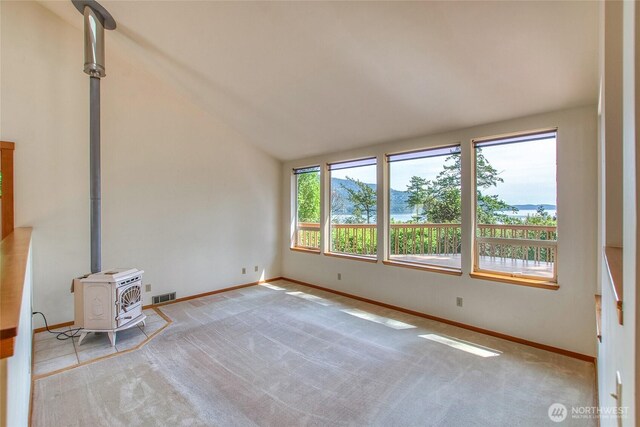 55 Langell Ln, Orcas Island, WA 98245 - unfurnished living room featuring a wood stove, carpet flooring, lofted ceiling, and baseboards