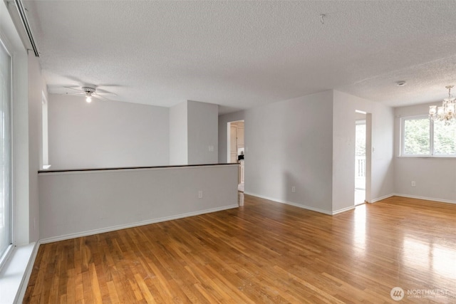14502 Main St, Bellevue, WA 98007 - unfurnished room featuring a textured ceiling, a chandelier, light wood-style flooring, a ceiling fan, and baseboards