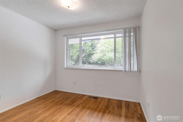 14502 Main St, Bellevue, WA 98007 - spare room with wood finished floors, a textured ceiling, and baseboards