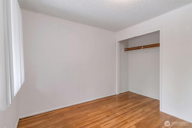14502 Main St, Bellevue, WA 98007 - unfurnished bedroom with wood finished floors, a closet, and a textured ceiling
