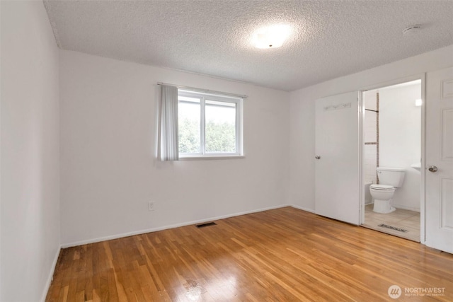 14502 Main St, Bellevue, WA 98007 - unfurnished bedroom featuring light wood finished floors, a textured ceiling, ensuite bath, and baseboards