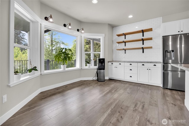 13800 27th Dr NW, Tulalip, WA 98271 - kitchen featuring stainless steel refrigerator with ice dispenser, white cabinetry, light stone counters, baseboards, and light wood-type flooring