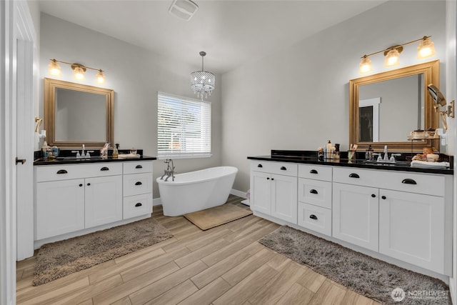 13800 27th Dr NW, Tulalip, WA 98271 - full bath with wood finished floors, a freestanding bath, two vanities, and a chandelier