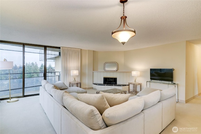 living room with light carpet, a wall of windows, a textured ceiling, baseboards, and a tile fireplace