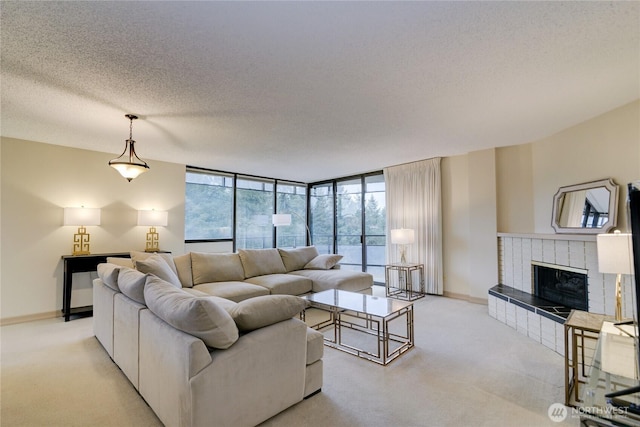 living area with light carpet, a glass covered fireplace, baseboards, a textured ceiling, and floor to ceiling windows