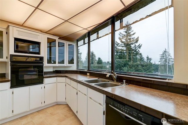 kitchen featuring black appliances, a sink, white cabinets, and glass insert cabinets