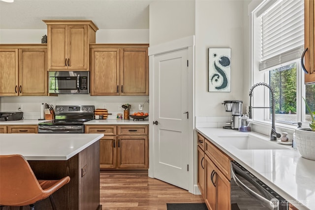 266 Fir Rd, Ariel, WA 98603 - kitchen featuring stainless steel appliances, a sink, light countertops, wood finished floors, and brown cabinetry