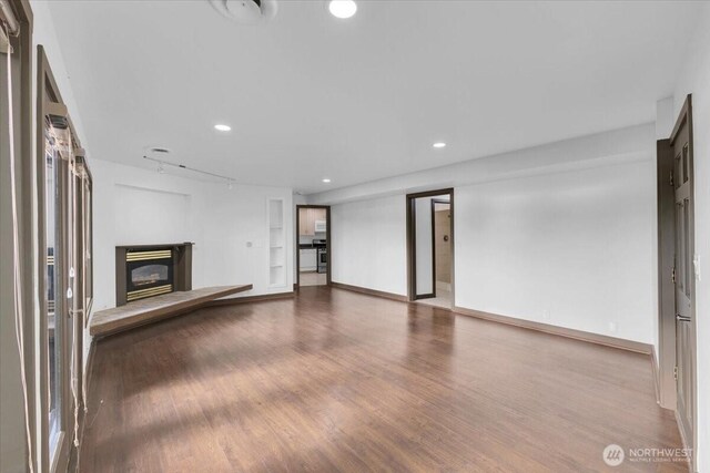16015 Inglewood Rd NE, Kenmore, WA 98028 - unfurnished living room with a glass covered fireplace, wood finished floors, recessed lighting, built in shelves, and baseboards