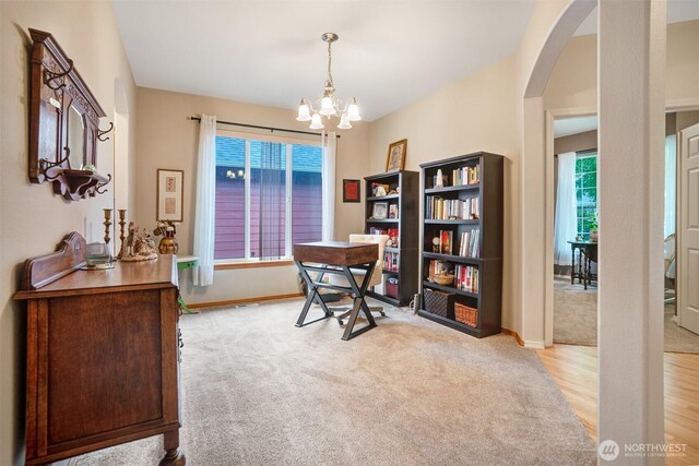 office space with arched walkways, light colored carpet, a chandelier, and baseboards