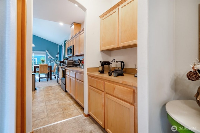 kitchen featuring electric range, light brown cabinets, stainless steel microwave, vaulted ceiling, and light countertops