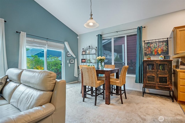dining room with lofted ceiling and light carpet