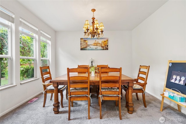 carpeted dining area with a chandelier and baseboards