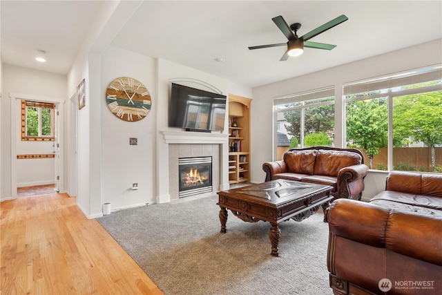 living area with a ceiling fan, a fireplace, baseboards, light wood-type flooring, and recessed lighting