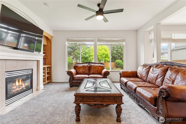 carpeted living room featuring a ceiling fan, a fireplace, and baseboards