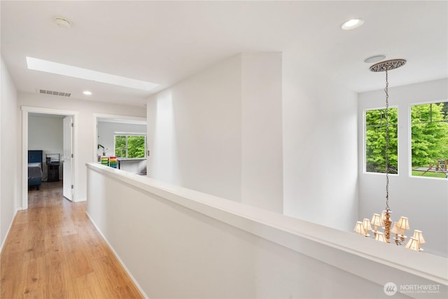 hall featuring a skylight, baseboards, light wood-type flooring, and recessed lighting