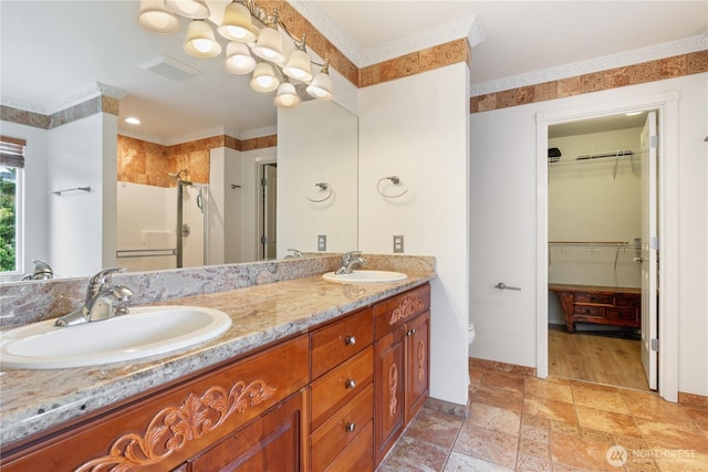 full bathroom featuring a stall shower, double vanity, a walk in closet, baseboards, and stone finish flooring