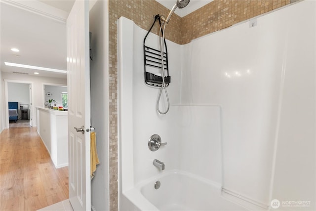 bathroom with bathing tub / shower combination, wood finished floors, and recessed lighting
