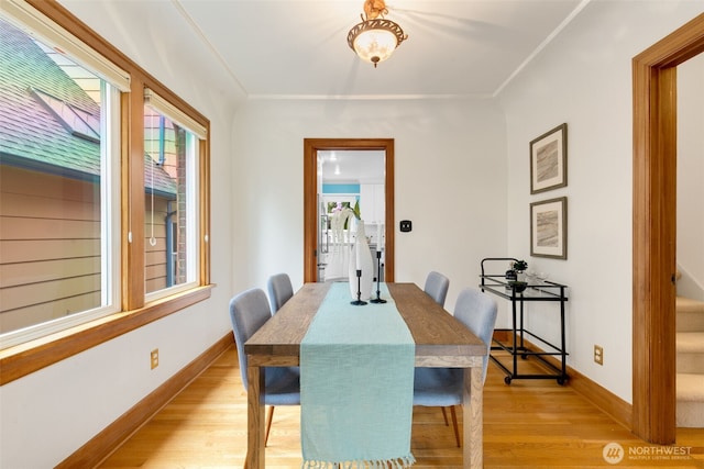 dining room featuring light wood finished floors, baseboards, and crown molding