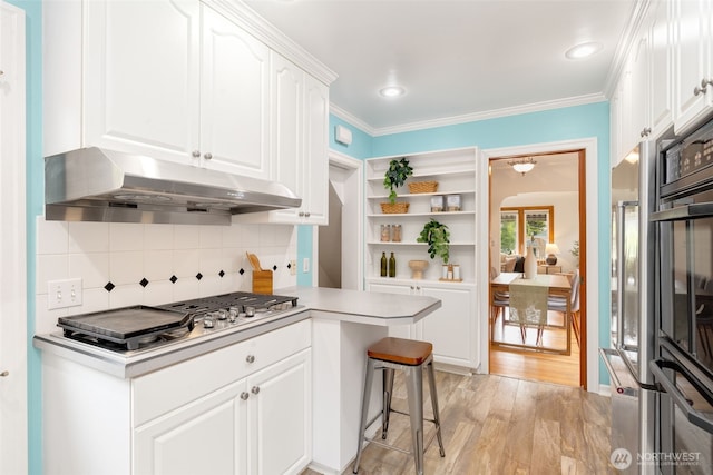 kitchen with under cabinet range hood, white cabinetry, open shelves, stainless steel gas stovetop, and light wood finished floors