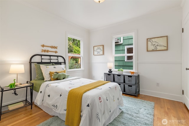 bedroom with ornamental molding, wood finished floors, and baseboards