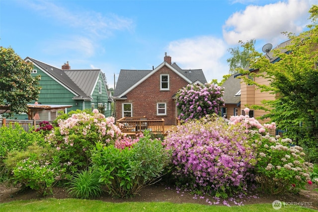 back of house with a chimney, brick siding, and a wooden deck