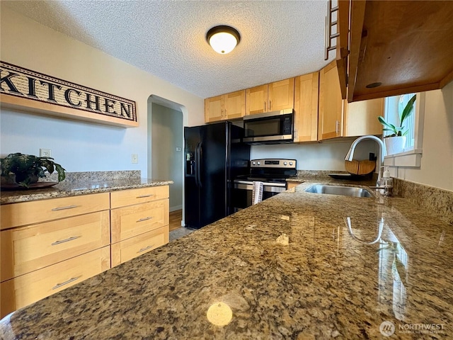 10644 19th Ave SW, Seattle, WA 98146 - kitchen with appliances with stainless steel finishes, a sink, dark stone countertops, light brown cabinetry, and a textured ceiling