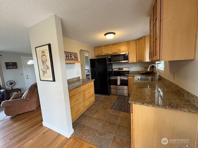 10644 19th Ave SW, Seattle, WA 98146 - kitchen with stainless steel appliances, a sink, a textured ceiling, dark stone countertops, and open floor plan