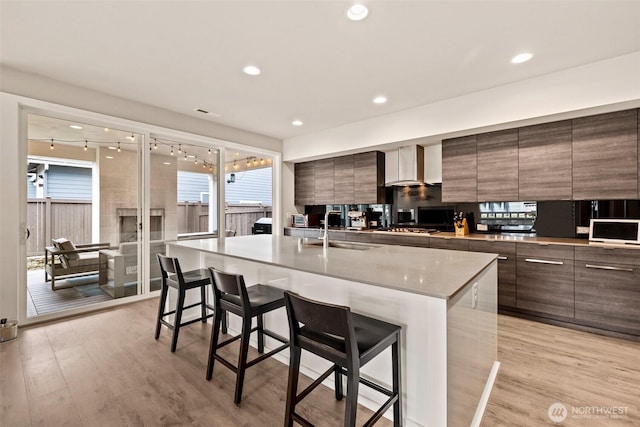 24821 237th Ln SE, Maple Valley, WA 98038 - kitchen featuring modern cabinets, wall chimney range hood, a sink, a kitchen breakfast bar, and recessed lighting