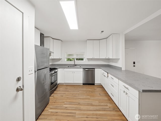 35603 Military Rd S, Auburn, WA 98001 - kitchen featuring appliances with stainless steel finishes, a peninsula, light wood-style flooring, and white cabinetry