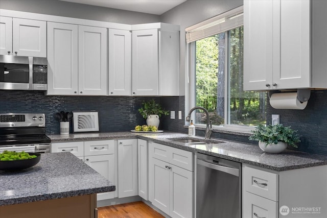 kitchen with appliances with stainless steel finishes, a sink, white cabinetry, and decorative backsplash