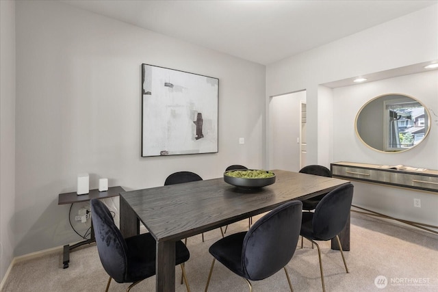 dining area featuring light carpet and baseboards