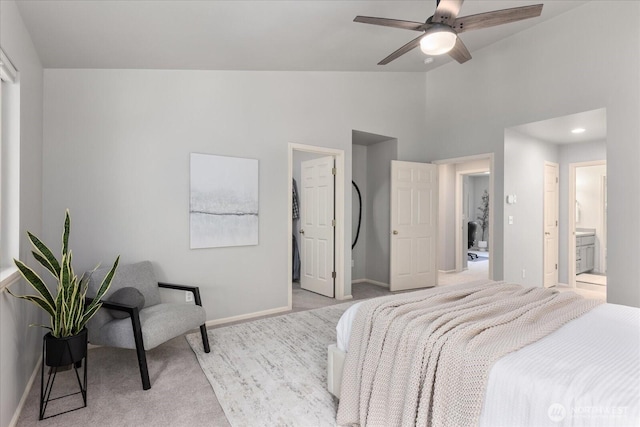 bedroom featuring carpet floors, baseboards, ensuite bath, and high vaulted ceiling
