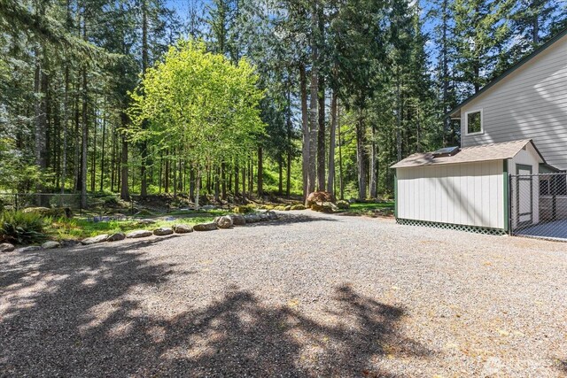 view of yard with an outbuilding, fence, and a storage shed