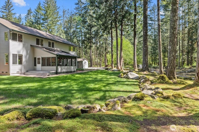 view of grassy yard featuring a shed, an outdoor structure, and a sunroom