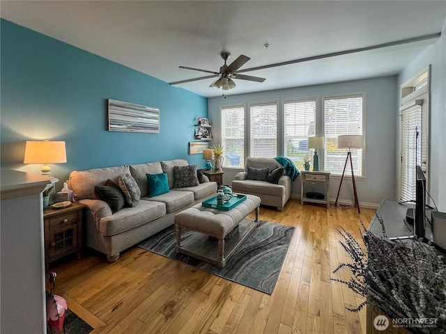 living area with ceiling fan, light wood-style flooring, and baseboards