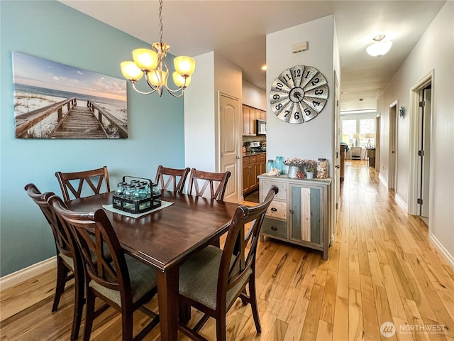 dining area with a chandelier, light wood-style flooring, and baseboards