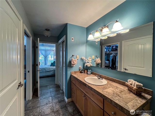 bathroom with vanity, baseboards, stone finish flooring, and connected bathroom
