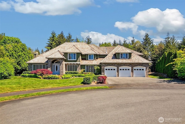 view of front of property featuring stone siding, concrete driveway, a front yard, and a garage