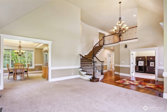 foyer featuring a chandelier, high vaulted ceiling, carpet flooring, stairway, and baseboards