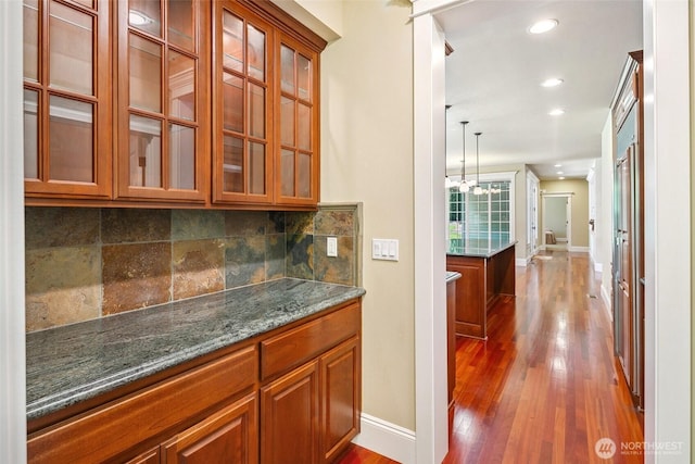 bar area featuring baseboards, backsplash, dark wood-type flooring, recessed lighting, and a chandelier