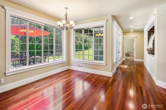 unfurnished dining area with a chandelier, healthy amount of natural light, wood finished floors, baseboards, and recessed lighting