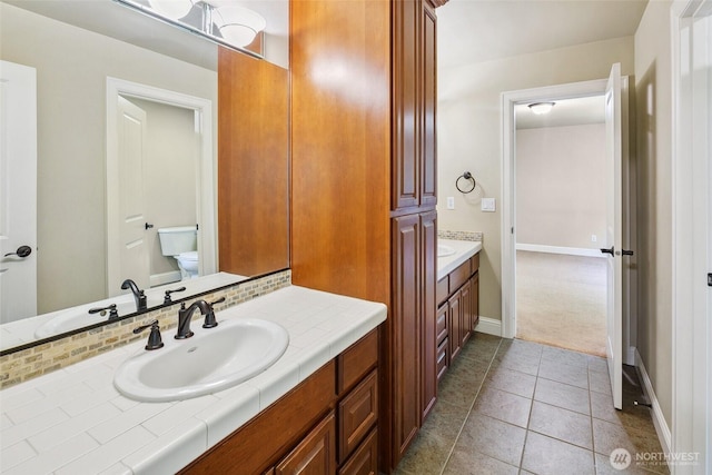 bathroom with vanity, toilet, baseboards, and tile patterned floors