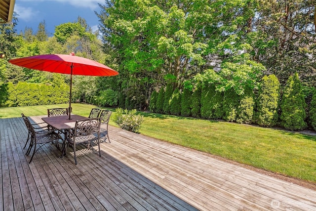 wooden terrace featuring a lawn, outdoor dining space, and view of scattered trees