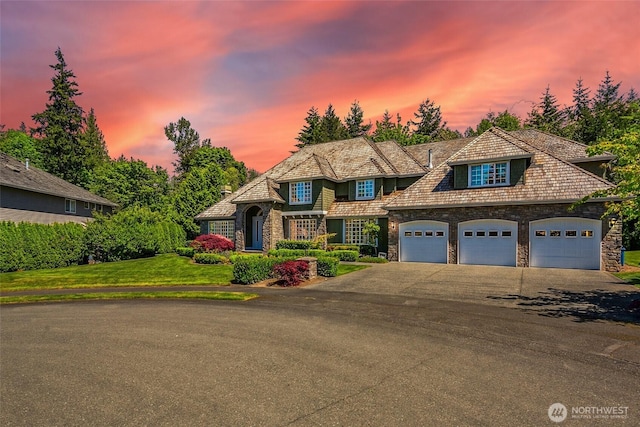 view of front of house featuring stone siding, asphalt driveway, and an attached garage
