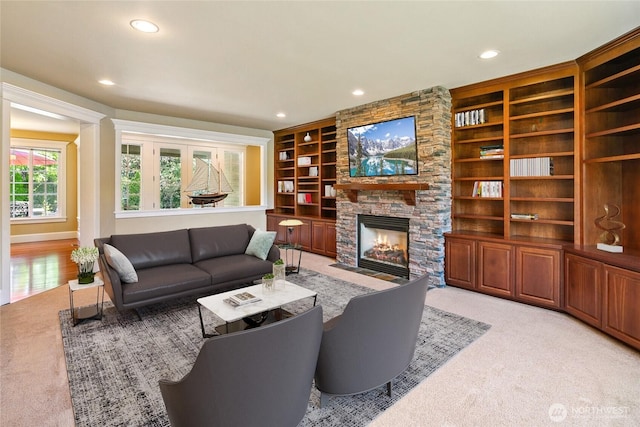 living area with recessed lighting, light carpet, a stone fireplace, and built in features