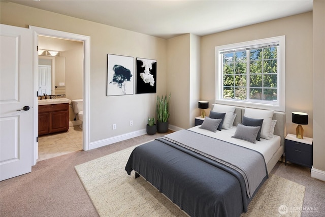 bedroom featuring light carpet, ensuite bath, and baseboards