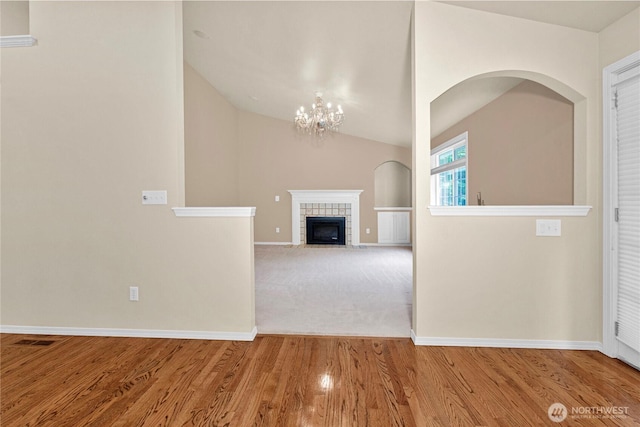 2222 60th Ln NW, Olympia, WA 98502 - unfurnished living room featuring baseboards, lofted ceiling, wood finished floors, a chandelier, and a tile fireplace