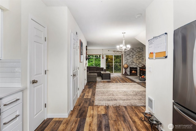 hall featuring dark wood finished floors, a chandelier, and baseboards