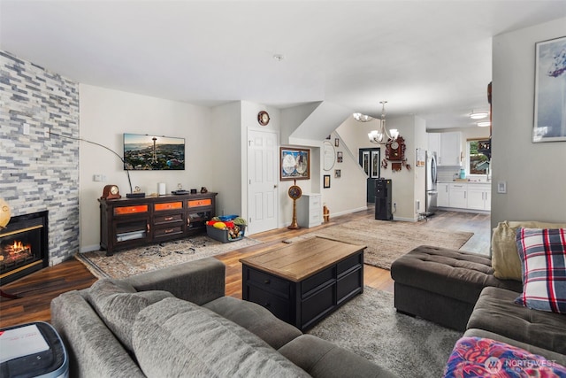 living room featuring a chandelier, wood finished floors, a fireplace, and baseboards