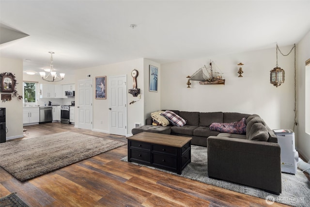 living area featuring a chandelier, dark wood-style flooring, and baseboards